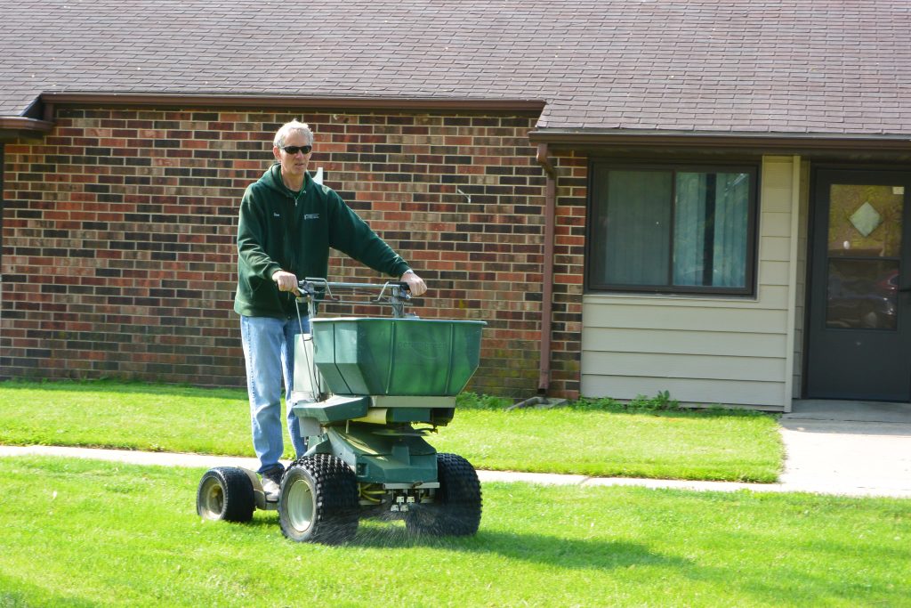 Green Valley employee operating riding fertilizer spreader at residence